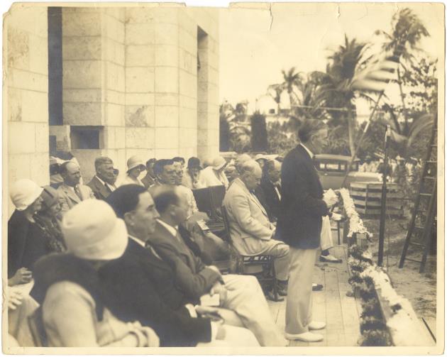 Dedication Ceremony and laying of cornerstone of Harvey Firestone outside of the Miami Beach Public Library, 1934 - Photograph, recto: [View of Harvey S. Firestone, speaking, Dr. Jos H. Adams, Irving Collins, Clayton S. Cooper, C.W. Chase, John B. Orr, Dr. Elisha A. King, Mrs. J. E. Adams, Mrs. R.L. Ellis, Mrs. Helen Terry, Lena Ford and Bertha Aldrich, head librarian]