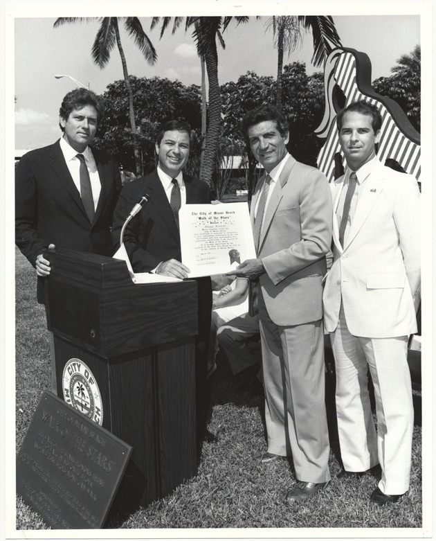 Veteran's Day and Burt Reynolds celebrations and presenting awards - Photograph, recto: [View of Commissioner Alex Daoud, Mayor Fromberg presenting proclamation to Sergio Franchi and Commissioner Bruce Singer in the Walk of Stars. The Mermaid statue (1971) by Roy Lichtenstein in the back]