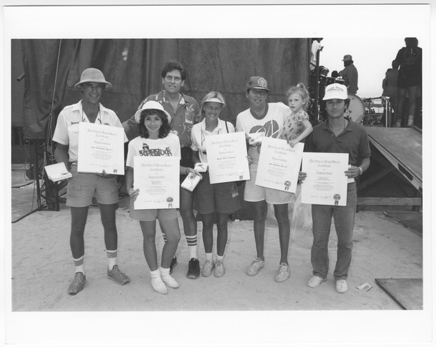 City officials and concert during the All American Weekend, July 1982 - Photograph, recto: [Left to right, John Cunningham (Penrod's), Lucia Hausman (Trendz USA), Mayor Alex Daoud, Melissa Turtle (Coppertone), Dean Goodman (LOVE 98), and Brad Krasser (President of Festival Ventures) during the July 4th All American Weekend Celebration, July 4, 1986]