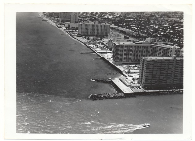 Aerial views of the City of Miami Beach and the City of Miami 1960-1970 - Photograph, recto: [Aerial view of Bal Harbor, Collins Avenue, and a boat facing south]
