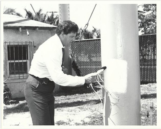 Miami Beach Mayor Alex Daoud at official city events and proclamations, 1980s - Photograph, recto: [Mayor Alex Daoud drawing his name in the Miami Beach water tower, July 1987]