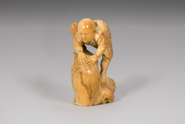 Netsuke: boy holding minogame - artifact front view