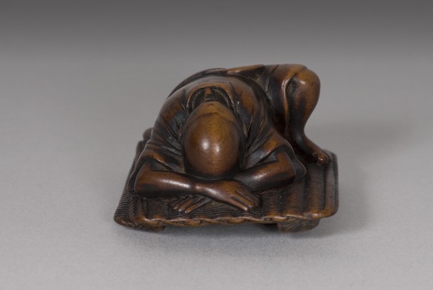 Netsuke: old farmer asleep on a tatami mat - artifact front view