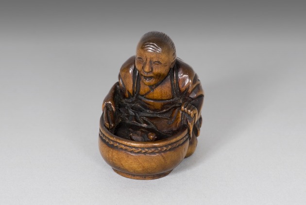 Netsuke: old lady holding a bucket containing a bird - artifact front view