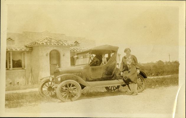 Women sitting on car in front of house
