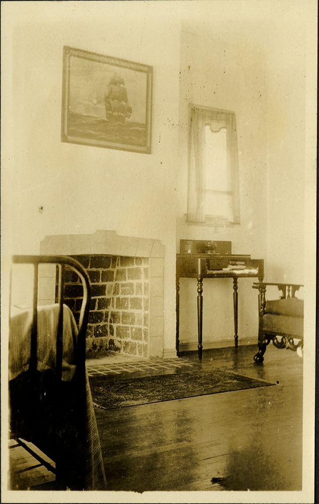 Interior view - fireplace, chair and desk inside home, painting of ship on wall
