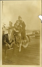 Group of two men and two women posing in and next to a car