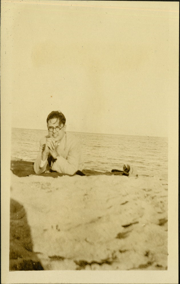 Ashton + B.W. - At sea WAD [Walter Ashton Drummond] - Man with hands under chin smiling at camera at beach