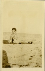 Ashton + B.W. - At sea WAD [Walter Ashton Drummond] - Man with hands under chin smiling at camera at beach