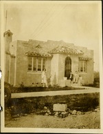 Two women and man sitting in front of house