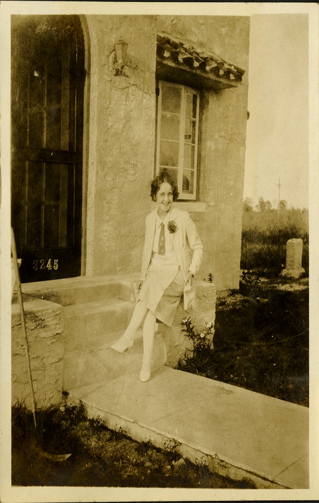 Woman sitting and smiling looking at camera in front of house