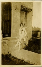 Woman sitting and smiling looking at camera in front of house