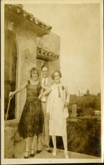 Man and two women smiling at camera in front of house