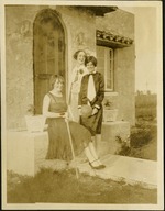 Three women smiling at camera in front of house