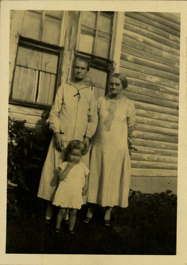 Two older women standing behind child, looking at camera