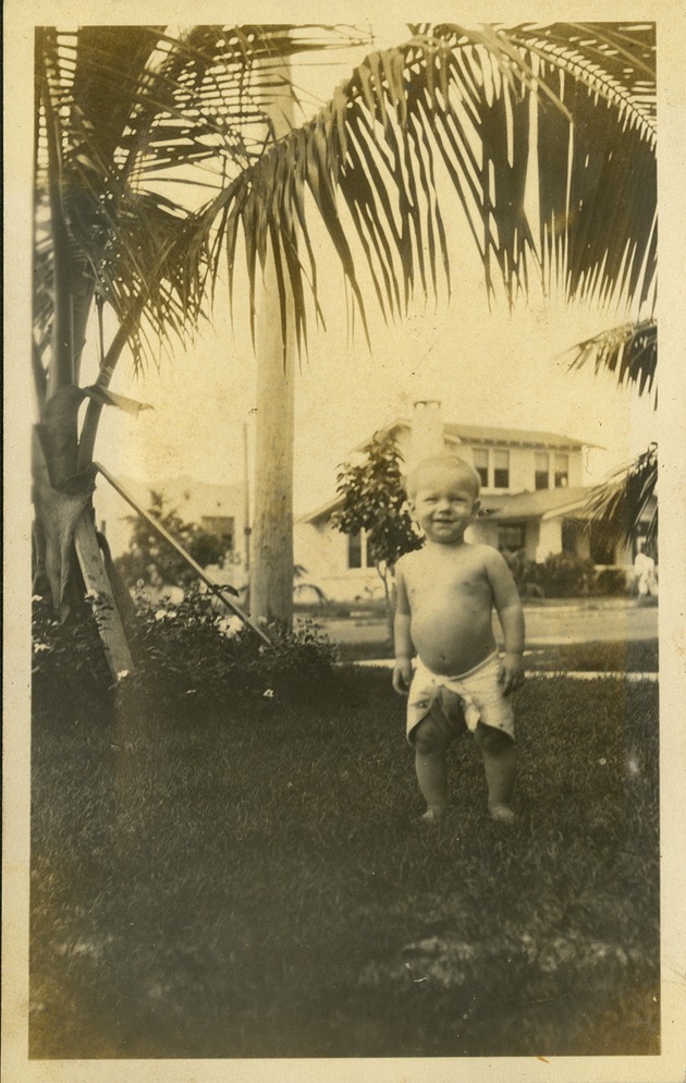 Baby standing in grass smiling at camera