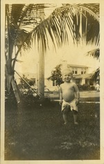 Baby standing in grass smiling at camera