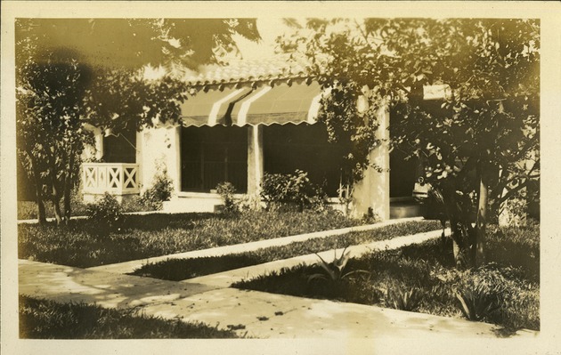 View of house from outside, grass, tree, awnings on windows