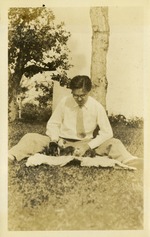 [1929] Man with puppies on blanket in grass