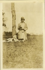 Woman holding puppy with dog and other puppies in grass