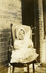Baby sitting in small chair outside home - Geo Jr.
