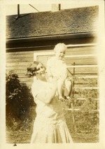 Woman raising a baby in her arms outside home