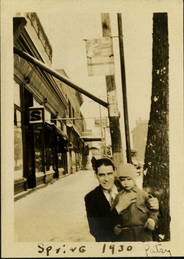 Spring 1930 - Patsy - Man holding small child on side walk near shops