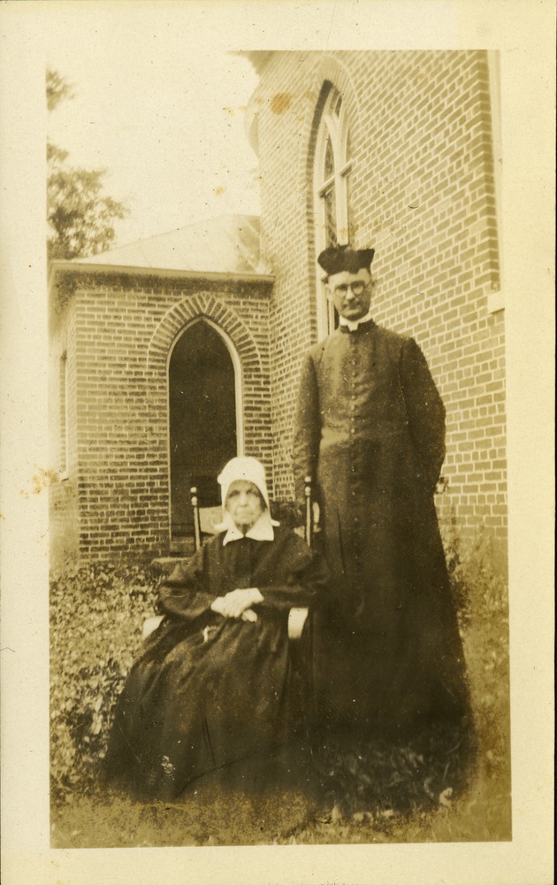 Joe FitzGibbon priest in Key West with seated nun in an open courtyard