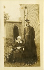 Joe FitzGibbon priest in Key West with seated nun in an open courtyard