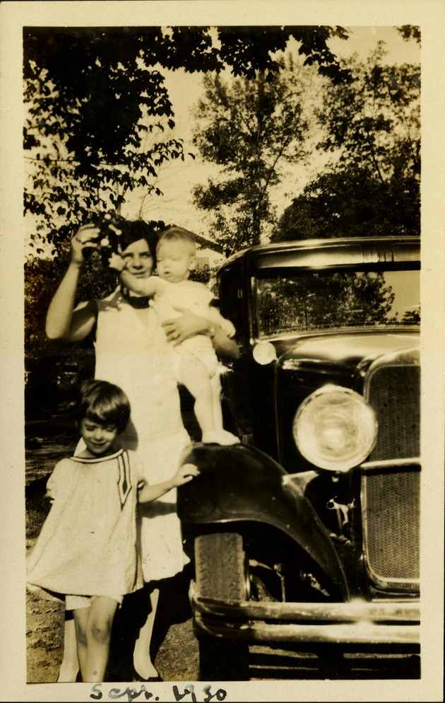 Sept. 1930 - Woman holding a baby and child next to car