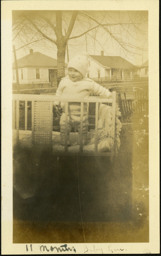 11 months Baby Lou - Baby in hat standing in crib outside