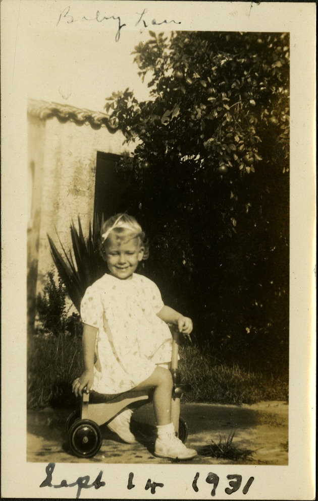 Baby Lou -  Sept 14 1931 - Smiling toddler sitting on bike