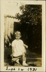 Baby Lou -  Sept 14 1931 - Smiling toddler sitting on bike