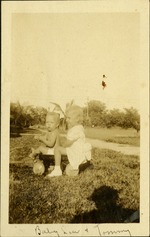 Baby Lou and Tommy - Two small children sitting in wagon in grass