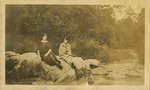 Sis and Eva; Two women sitting on rock near river