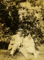 Man in hat and woman sitting in grass