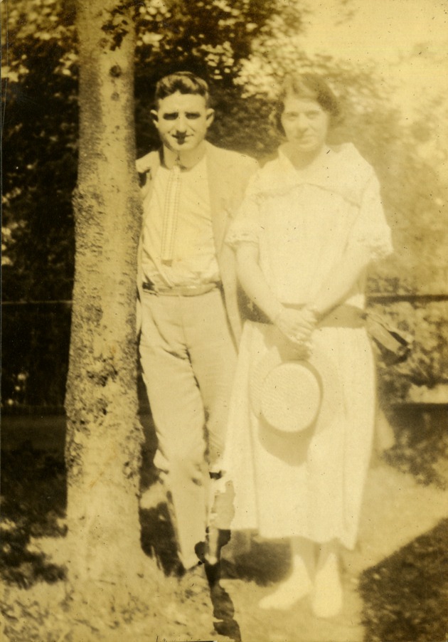 Man and woman holding hat next to tree