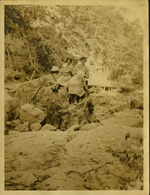 Two women and man sitting on rock