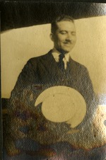 Man holding hat smiling, eyes closed