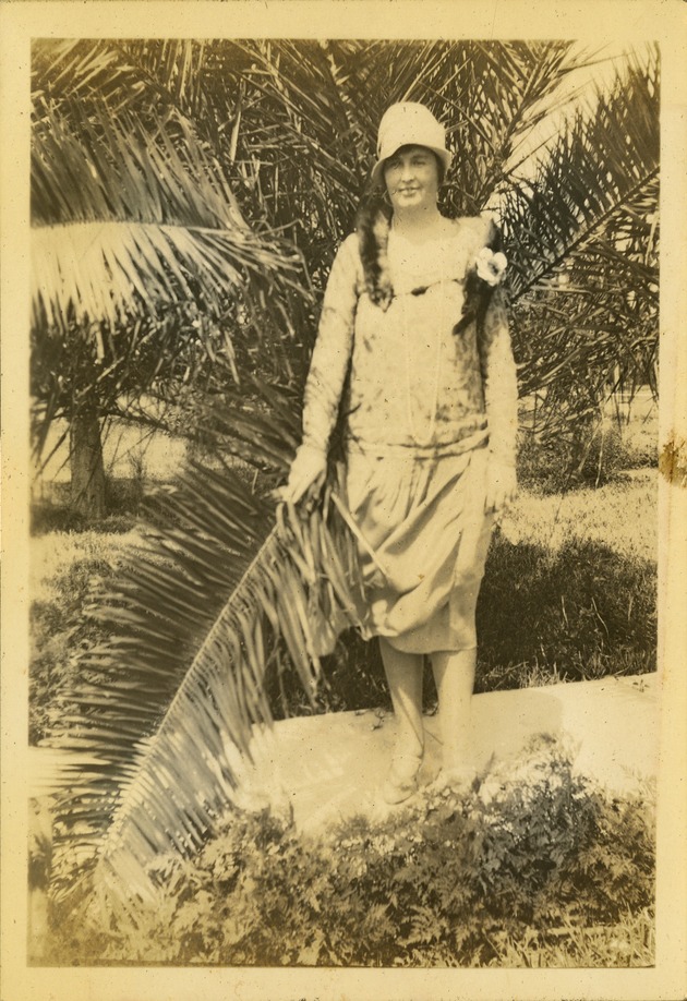 Woman in hat holding palm frond