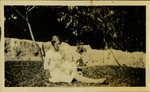 Woman holding baby, sitting in grass