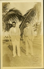 Two men standing in front of palm trees