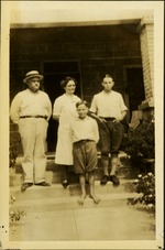 two men, woman, and young boy standing on house steps