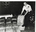 Sgt. Richard Asker posing with bales of marijuana