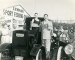 [1956-12-10] James Melton and woman standing on antique car at Lyman's dock, 1956