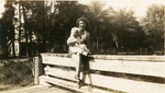 J. DeLand and baby sitting on old wooden bridge