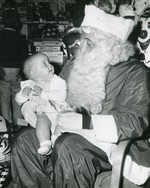 Santa Claus holding a smiling baby, 1962