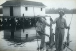 Two Lantana fishermen with fish in front of boathouse, c. 1940