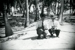 Two men in Manalapan grove holding pigs, c. 1925