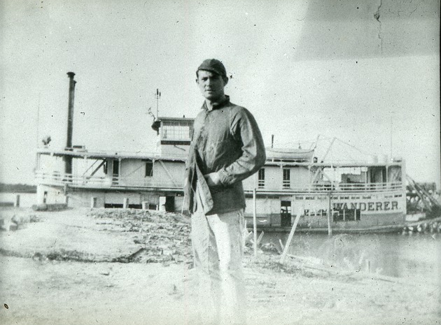 Man standing on shore in front of steamboat Wanderer, c. 1906